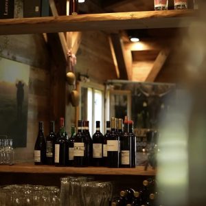 Weinbar in der Wagyu-Hütte – Flaschen und Gläser auf Holztheke, stimmungsvolles Licht