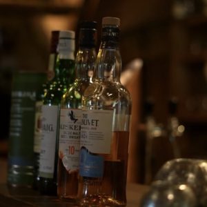 Whiskyflaschen auf rustikaler Holztheke in der Wagyu-Hütte – stimmungsvolles Setting fürs Whisky Tasting