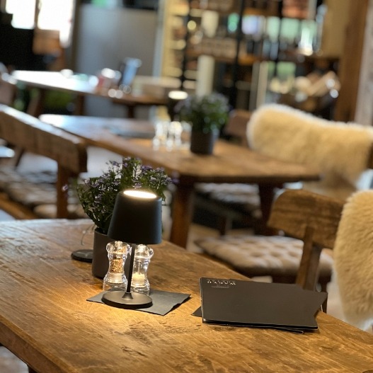 Gemütliche Sitzplätze in der Wagyu-Hütte mit Holztischen, Blumen und stimmungsvoller Beleuchtung