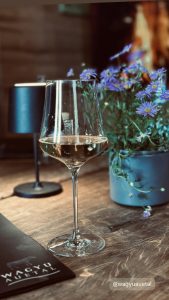 Holztisch in der Wagyu-Hütte mit Weinglas und eleganter Tischleuchte